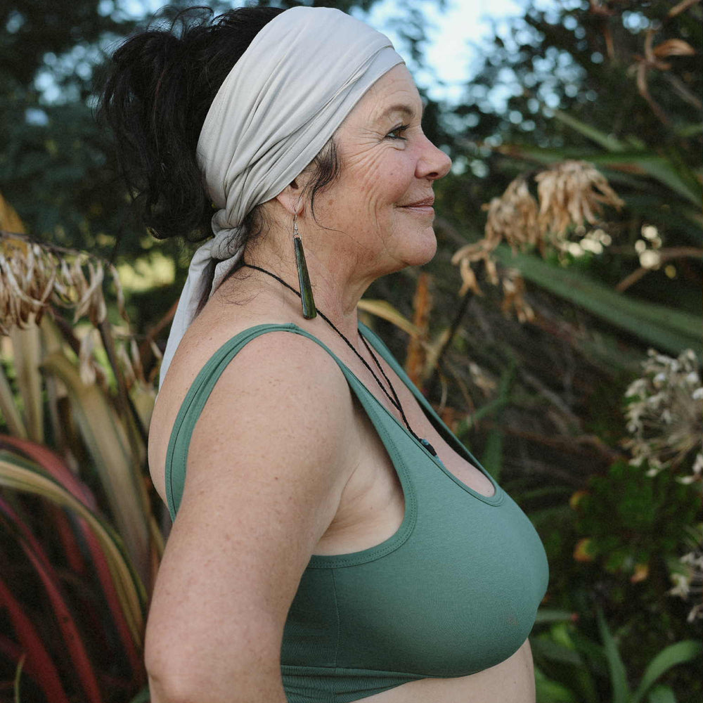 Woman wearing a green sports bra outdoors with plants in the background