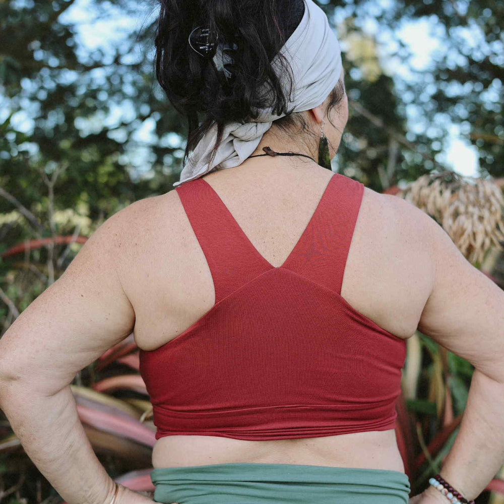 Person wearing a red sports bra and green shorts outdoors with trees in the background