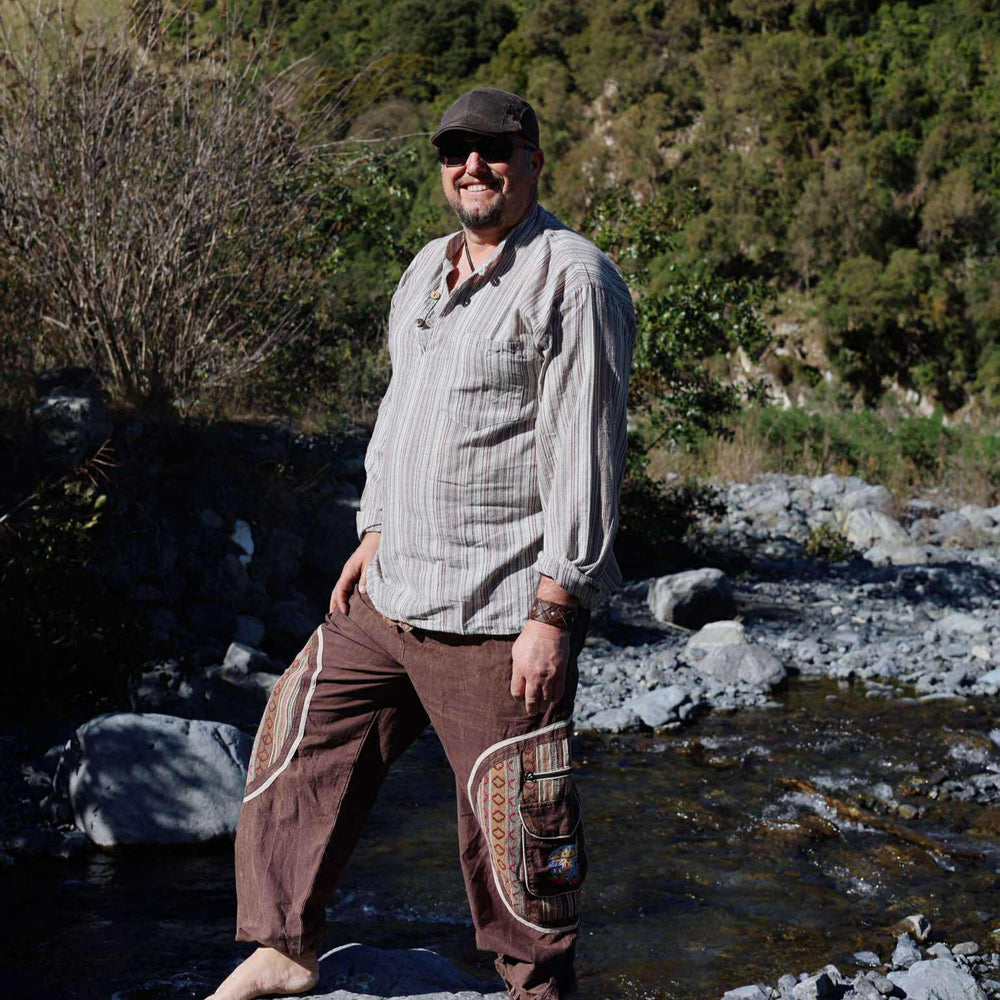Man standing by a stream with mountains in the background